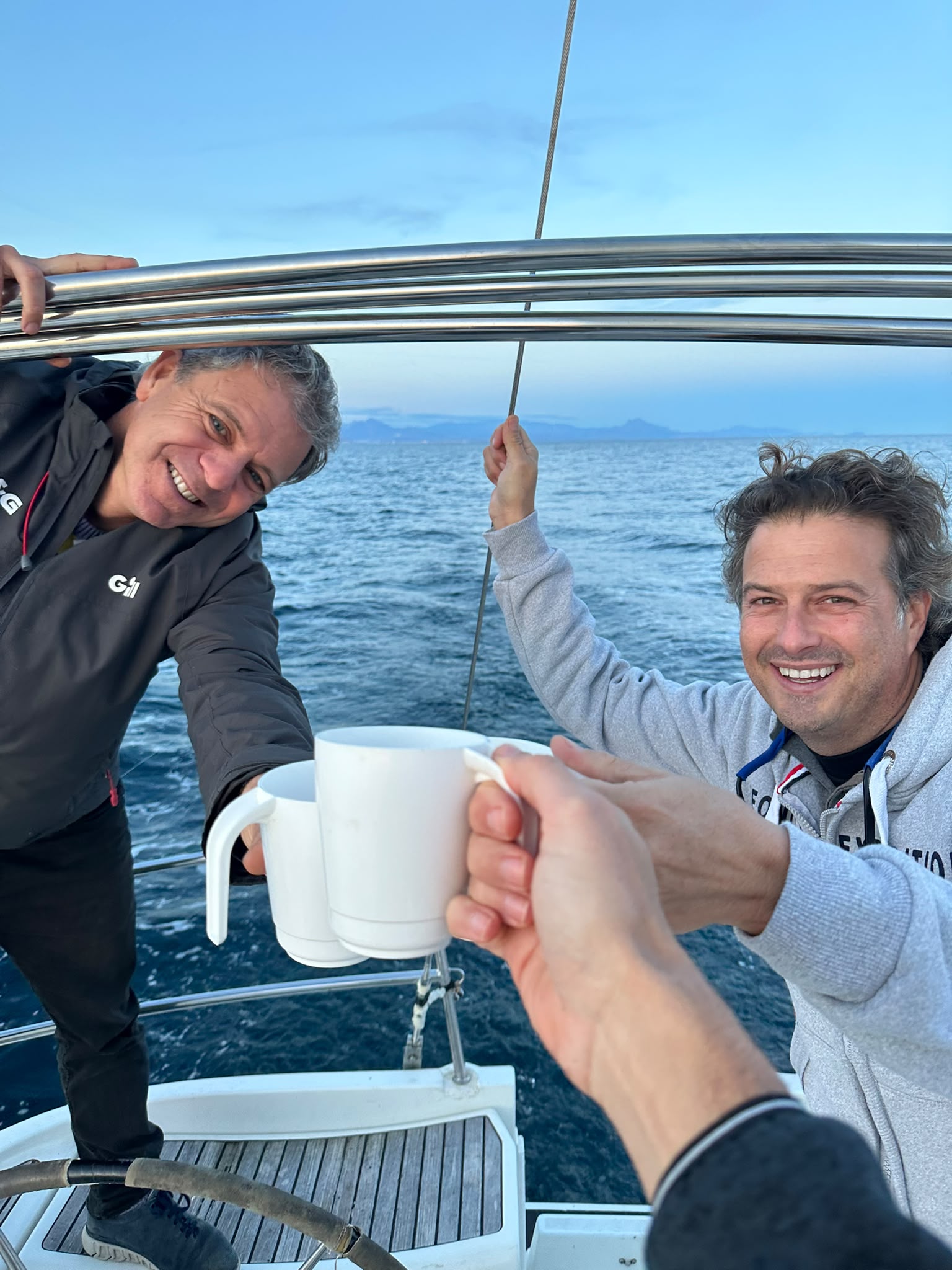Tripulantes brindan en la cubierta de un velero durante una navegación por la costa.