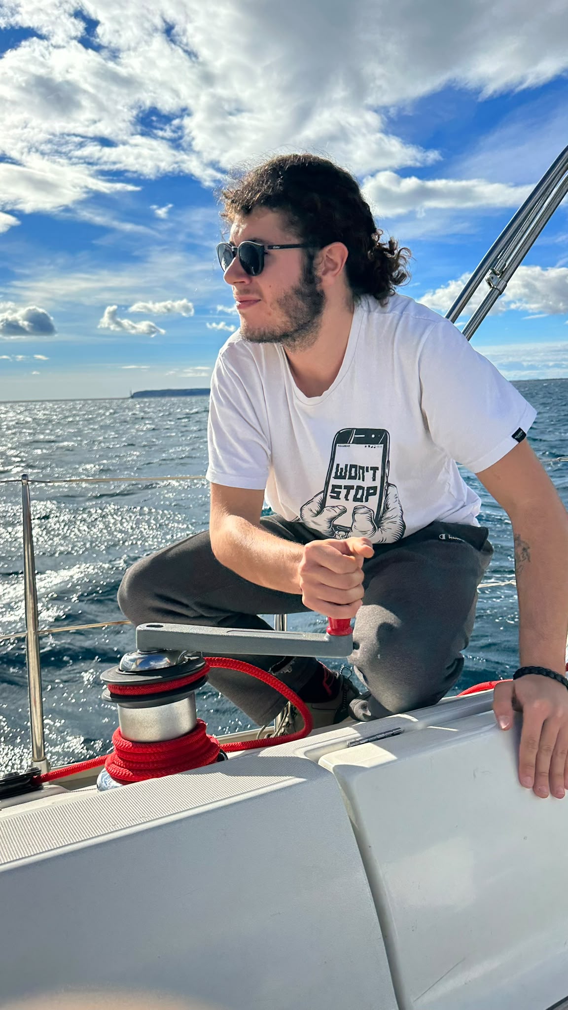 Tripulante acciona el winche de un velero durante una práctica de navegación a vela.