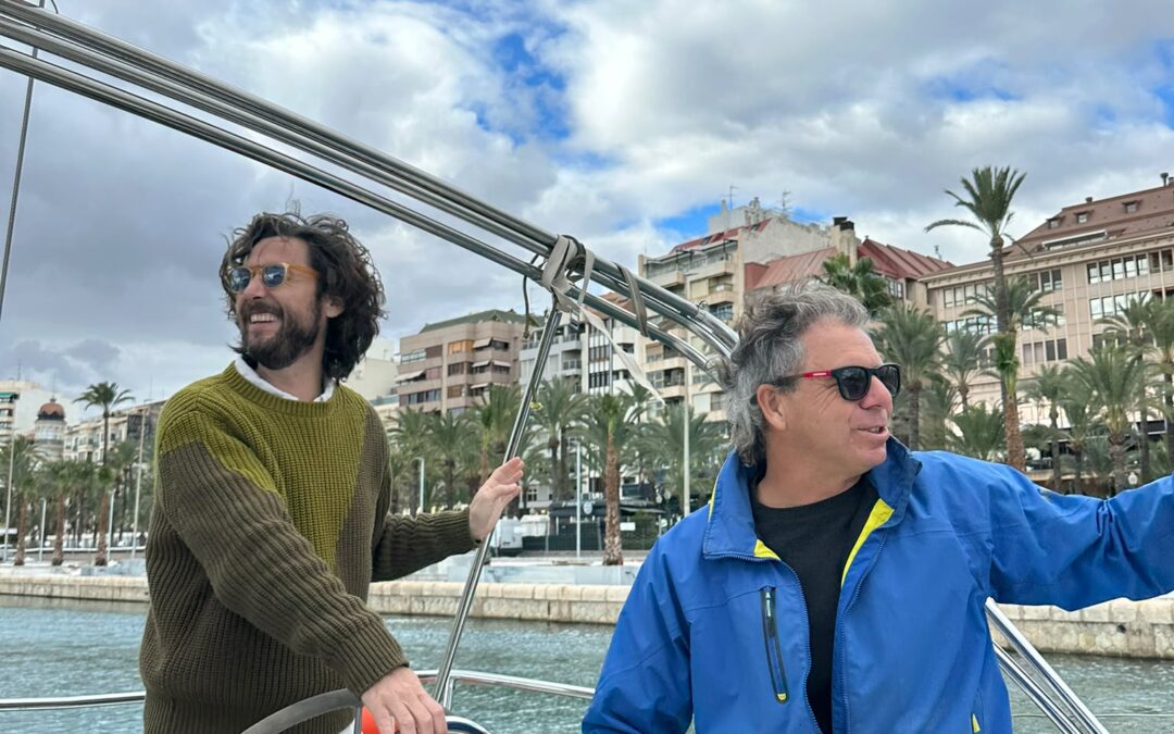 Tripulantes a bordo de un velero en el puerto de Alicante durante una práctica de navegación.