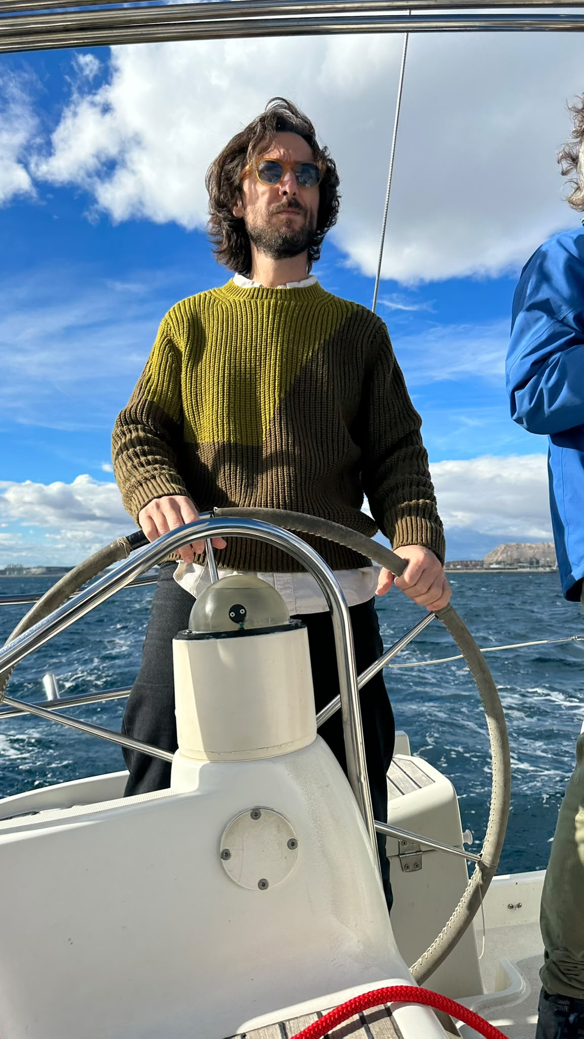 Tripulante al timón de un velero durante una práctica de navegación a vela en el mar.