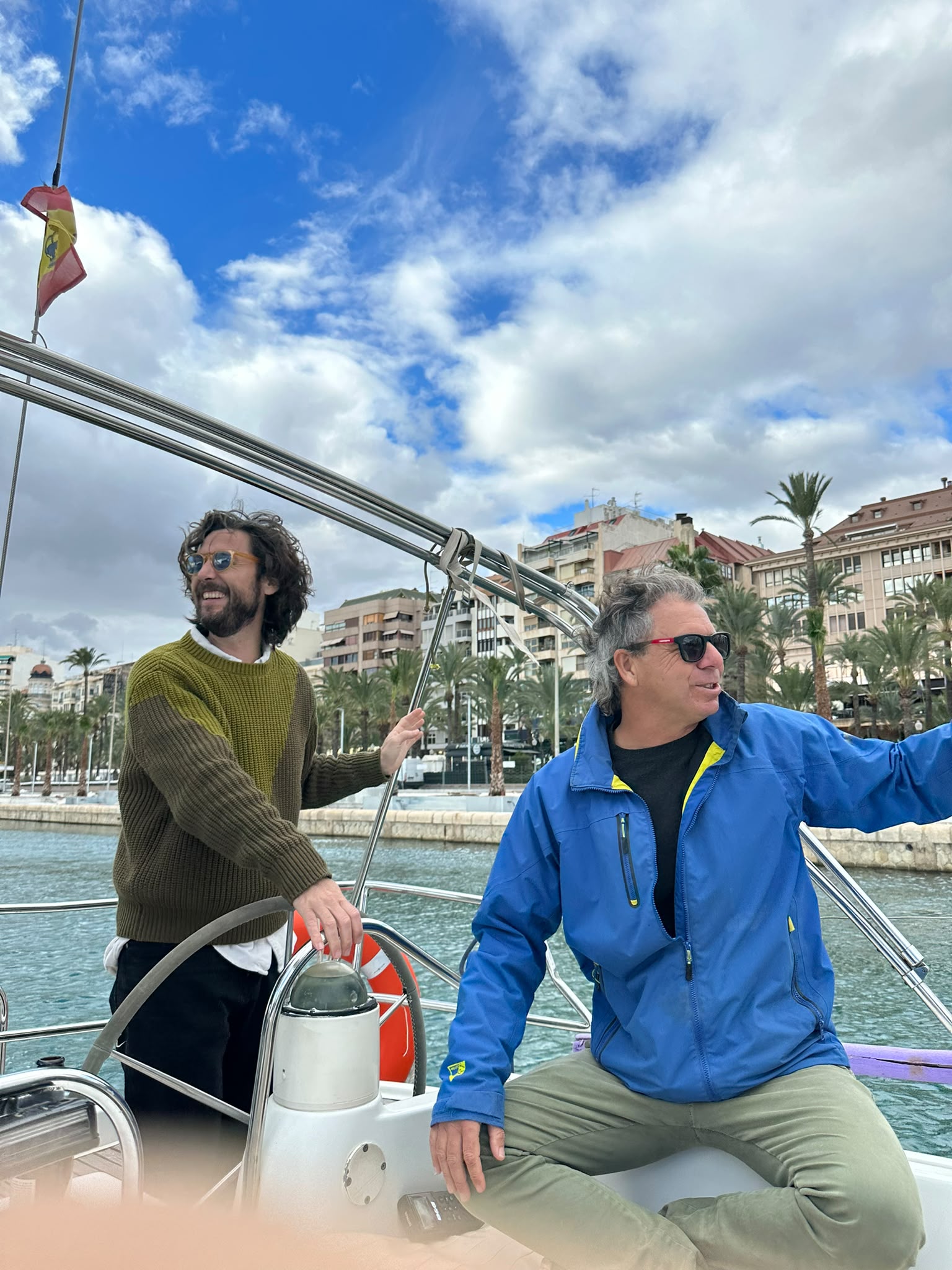 Tripulantes a bordo de un velero en el puerto de Alicante durante una práctica de navegación.